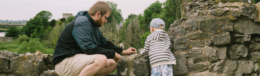 an adult and a child standing next to a wall