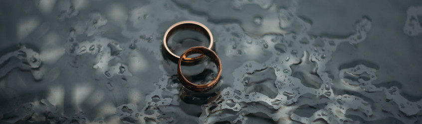 two wedding rings on a black watery surface