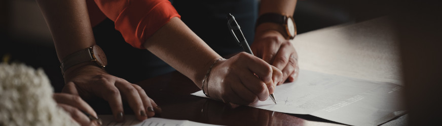 a person signing a document with a pen